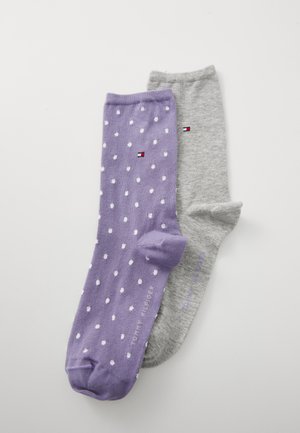 Purple sock with white polka dots and a gray sock side by side, both featuring a small logo and branding text.