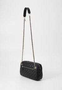 Borsa in pelle trapuntata nera con forma rettangolare, dotata di una tasca frontale con zip e una tracolla a catena con elementi neri.