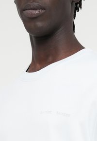 Λευκό βαμβακερό φούτερ με ριμπ γιακά σε σχέδιο crew και διακριτικό ανάγλυφο λογότυπο στο στήθος. Ομαλή υφή και άνετη εφαρμογή.