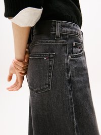 Os jeans de denim escuro apresentam uma cintura de altura média, um desbotamento subtil e uma etiqueta preta na parte de trás. Os bolsos traseiros incluem costura decorativa.