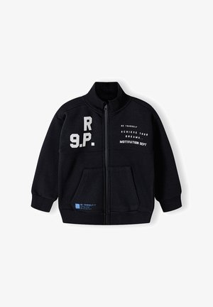 Musta fleece-zipup-takki, jossa on seisova kaulus, etutaskut, painettu teksti ja kontrastivärit vasemmalla puolella ja helmassa.