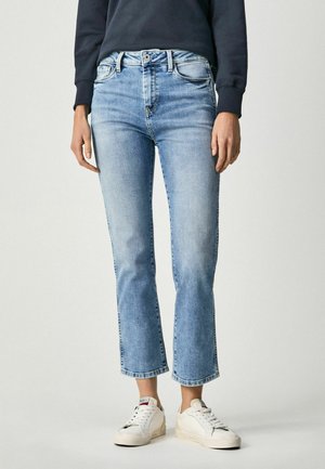 Ljusblå denimjeans med en kort, utsvängd bendesign. Har en medelhög midja, kontrasterande sömmar och subtil blekning. Bärs med vita sneakers.