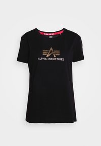 T-shirt en coton noir à manches courtes et col rond. Présente un logo en couleur dorée "ALPHA INDUSTRIES" avec un design géométrique.