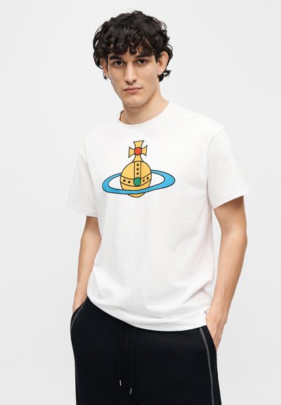 Λευκό βαμβακερό t-shirt με πολύχρωμο γραφικό που απεικονίζει ένα στέμμα και πλανήτες σε κίτρινο, μπλε και πράσινο. Με κοντά μανίκια και λαιμόκοψη γύρω από το λαιμό.
