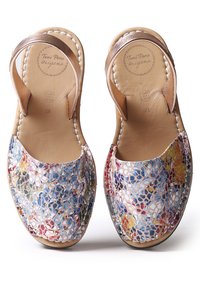 Leather sandals featuring a multicolored, woven upper with floral patterns, brown leather straps, and white stitching along the edges.