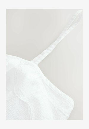 Weißes Stofftop mit einem strukturierten Muster, versehen mit einem dünnen, verstellbaren Träger und einem weichen, leicht gewelltem Erscheinungsbild. Keine sichtbaren Beschläge.