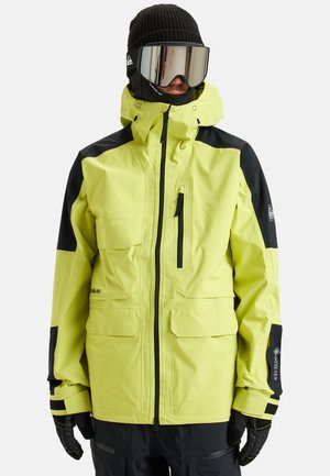 Jasnożółta wodoodporna kurtka z czarnymi akcentami, zamykanymi na zamek kieszeniami oraz wysokim kołnierzem. Posiada metkę GORE-TEX na rękawie.