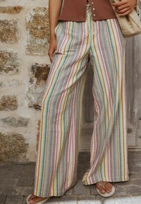 Mitmevärvilised triibulised laiade sääreosadega püksid tekstureeritud kangast, kus esinevad pastelsed ja maamaised toonid, elastse vöökohaga ning käetaskutega.