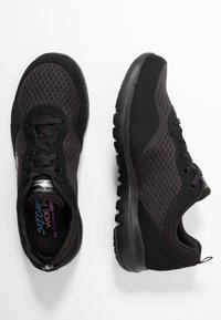 Svarta atletiska sneakers med nätpaneler, snörningsdesign och strukturerade sulor. Har förstärkt tå och stödjande arkitektur för komfort.