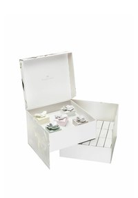 Weißes Geschenkpaket mit floralem Design, das kleine bunte Boxen enthält, die mit "Luft", "Erde" und "Feuer" beschriftet sind, jeweils mit dekorativen Akzenten.