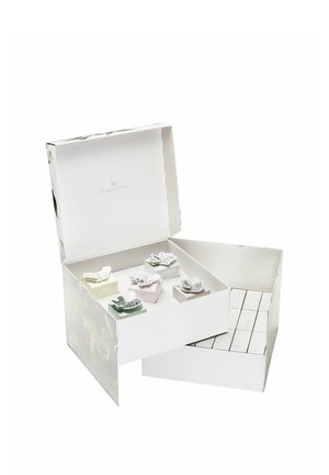 Coffret-cadeau blanc avec un design floral, contenant de petites boîtes colorées étiquetées "Air", "Terre" et "Feu", chacune ornée d'accents décoratifs.