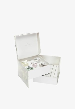 Weißes Geschenkpaket mit floralem Design, das kleine bunte Boxen enthält, die mit "Luft", "Erde" und "Feuer" beschriftet sind, jeweils mit dekorativen Akzenten.