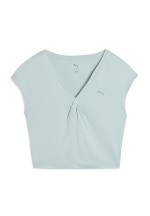 Jasnoniebieski krótki top uszyty z miękkiego materiału, z dekoltem w kształcie litery V, szczegółem skręconym z przodu oraz krótkimi rękawami. Logo Puma w dopasowanym kolorze.
