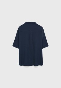 Camicetta a maniche corte blu navy con vestibilità morbida, colletto, tessuto testurizzato e dettaglio con piega sul retro.