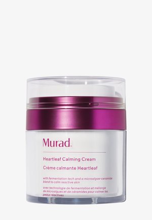 Crème apaisante Murad Heartleaf dans un pot transparent avec un couvercle métallique violet. Présente une crème blanche et des étiquettes en deux langues sur le devant.