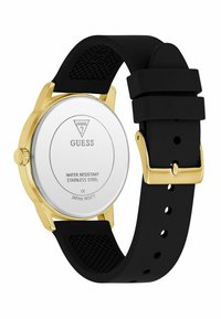 Gold and silver Guess watch showing a black silicone strap, with the rear view displaying a water-resistant description and brand logo.