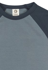 Tričko s krátkým rukávem světle modré barvy a tmavě modrými raglánovými rukávy. Měkká, texturovaná látka s kulatou logovkou na výstřihu.