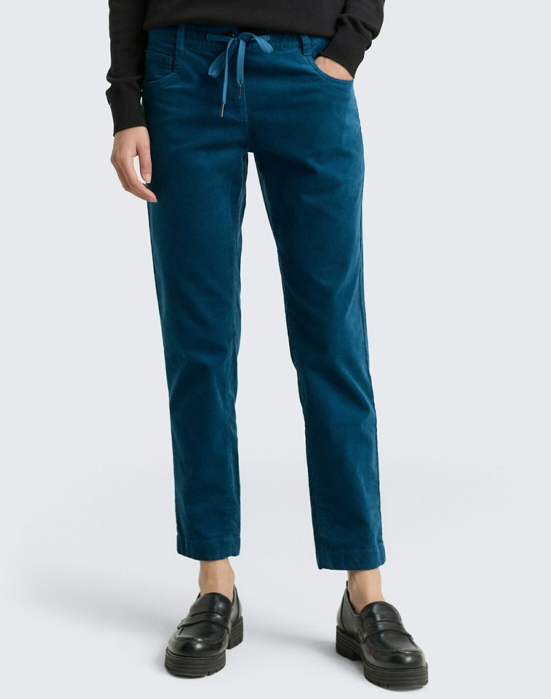Teal corduroy pants with a drawstring waist, featuring side pockets and a tapered leg design. Worn with black loafers.