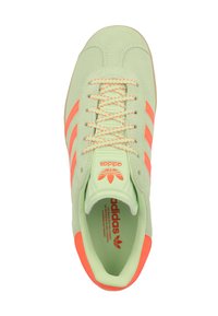 Gröna mockaskor med oranga ränder, rund tå och texturerade snören. Varumärket syns på tungan och innersulan.