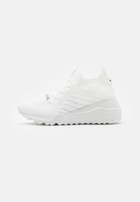 White athletic sneakers with a knit upper, featuring perforated detailing, flat laces, and a chunky rubber sole for traction.