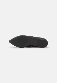 Zapato plano de cuero negro con punta afilada. Textura suave, con un detalle mínimo. Suela de goma con un patrón de tracción ondulado para un mejor agarre.
