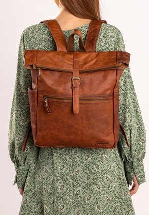 Brown leather backpack with roll-top design, featuring zippered pockets and adjustable straps. Smooth texture with subtle natural variations.