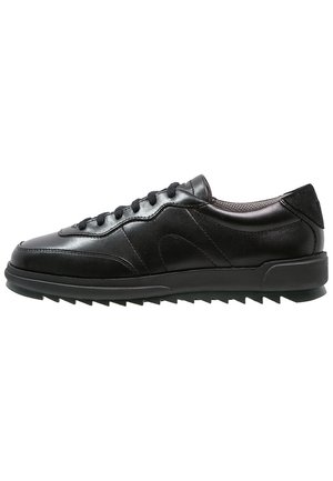 Czarny niski skórzany sneaker z sznurowaniem z przodu, wyściełanym kołnierzem i teksturowaną gumową podeszwą z ząbkowanym bieżnikiem.