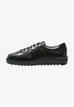 Czarny niski skórzany sneaker z sznurowaniem z przodu, wyściełanym kołnierzem i teksturowaną gumową podeszwą z ząbkowanym bieżnikiem.