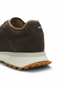Baskets en daim brun avec bordure beige, semelle épaisse blanche estampillée "BOSS" et semelle extérieure en caoutchouc gomme, vues de l'arrière.
