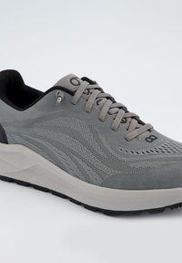 Chaussure de sport grise présentant un dessus en tricot texturé avec des accents en daim, des lacets ronds et une semelle intermédiaire épaisse blanche. Doublure intérieure noire.