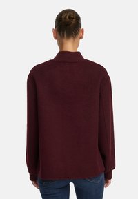 Bordeaux, oversized gebreide trui met een kraag, lange mouwen en geribde boorden, met een zachte textuur en een relaxte pasvorm. Achteraanzicht.