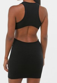 Černý žebrovaný crop top s designem na závodění a černou žebrovanou minisukní. Materiál má texturovaný povrch a přiléhavý střih.