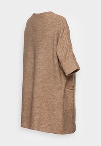 Ljust brunt oversized stickat tröja med ribbad textur, korta uppvikta ärmar och en sidficka. Slät tygfinish.