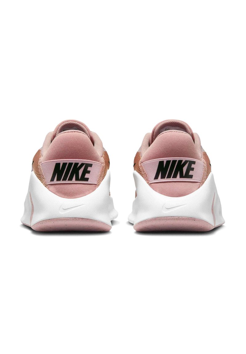 Nike sneakers in light pink and white with logo on heel. Features soft textile upper, cushioned sole, and smooth textures.