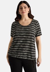 Top de manga corta a rayas en blanco y negro con escote redondeado y detalle de lazo en el lateral. Tejido suave con un ajuste relajado.