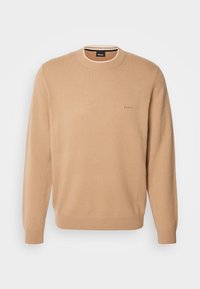 Pull beige à col rond avec manches longues, poignets et ourlet côtelés, et petit logo "BOSS" sur le côté gauche de la poitrine.