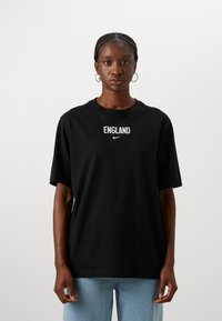 Black cotton t-shirt featuring "ENGLAND" text and Nike logo in white. Standard fit with short sleeves and a crew neckline.
