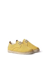 Scarpe in tela gialla con punta tonda, design con lacci e dettagli in pelle marrone. La suola in corda di juta naturale aggiunge una texture.