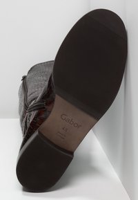 Botte en cuir brun foncé texturé avec un motif crocodile, dotée d'une semelle en caoutchouc lisse avec des rainures et d'un logo Gabor sur la semelle intérieure.