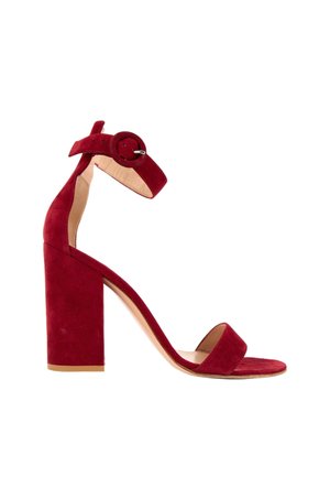 Sandale à talon haut en daim rouge, talon bloc, bout ouvert, bride à la cheville et boucle ronde sur fond blanc.