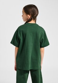 Grøn bomulds t-shirt med korte ærmer, rund hals og en afslappet pasform. Bagfra ses en glat tekstur og et enkelt design.