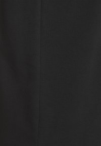 Gros plan sur un tissu noir avec une couture verticale subtile au centre.