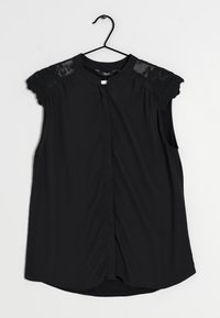 Blouse noire à manches courtes, avec des accents en dentelle transparente sur les épaules, fermeture avant par boutons et ourlet arrondi.