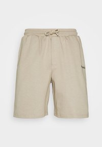 Shorts en coton beige avec une taille élastique et un cordon de serrage. Comprennent une poche avant et un discret logo sur le côté.