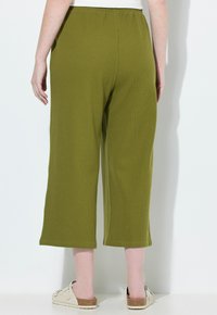 Groene, gestructureerde wijde pantalons met een elastische tailleband, in een cropped lengte en een gladde afwerking, gecombineerd met lichtgekleurde schoenen.