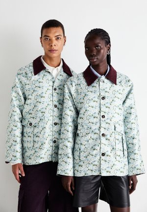 Blomstrete quiltede jakker i lyseblå med mørkebrune krager. Har frontlommer og knappelukking. Designet med løs passform.