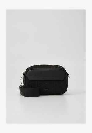 Mala de ombro Lacoste preta com padrão geométrico texturizado, logo suave, fecho de zip e alça ajustável. Forma retangular compacta.