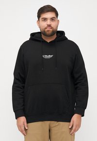 Zwarte hoodie van katoen, met een voorzak, trekkoordcapuchon en witte "JJ Studios" logo in het midden. Zachte textuur, casual fit.