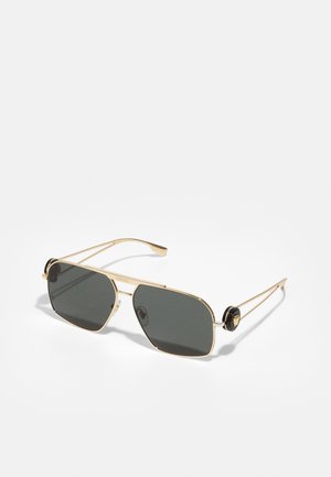 Óculos de sol de metal dourado com lentes retangulares em cinza escuro, apresentando detalhes pretos intrincados nas hastes e um detalhe de logótipo.
