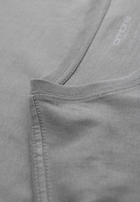 Šedé tričko s hladkou texturou, kulatým výstřihem a kontrastním prošíváním podél okrajů, s vytištěným názvem značky.